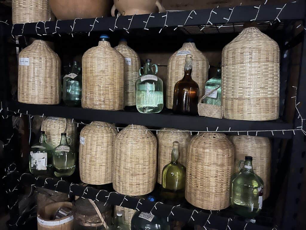 Detalle de una damajuana antigua de vidrio grueso con burbujas de aire, pieza de colección para maduración de mezcal en Oaxaca.