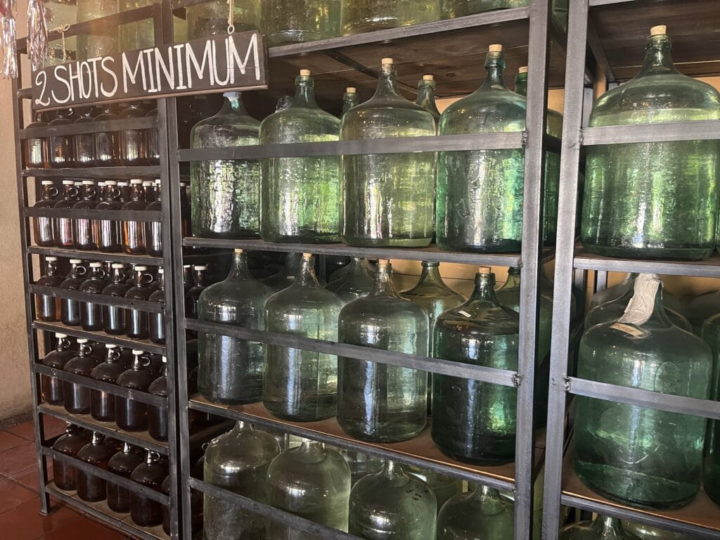 Damajuana de vidrio soplado artesanal de 20 litros con mezcal en reposo dentro de un palenque tradicional en Oaxaca.