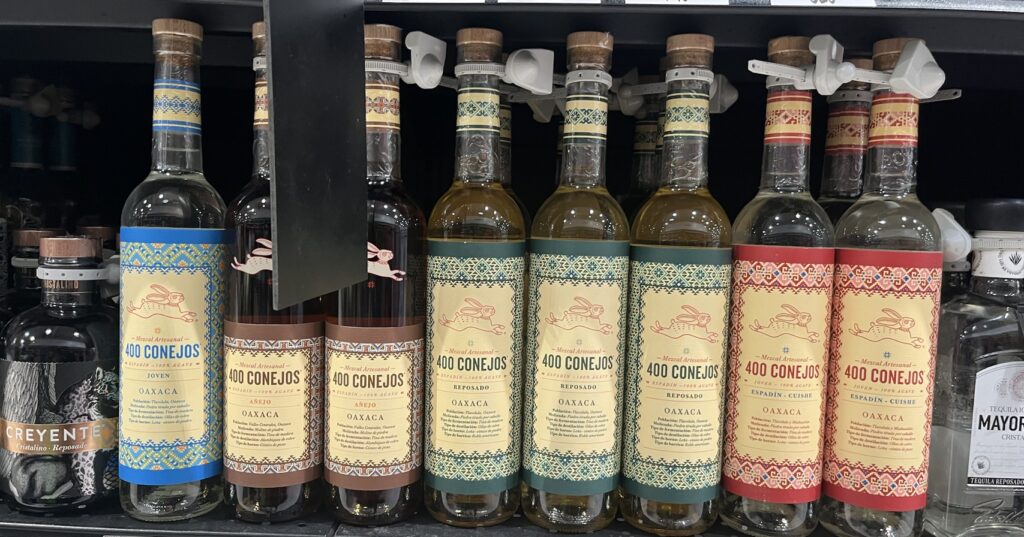 Botellas de la gama completa de Mezcal 400 Conejos en un estante de supermercado en Oaxaca.